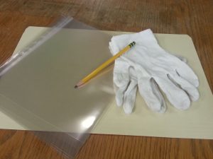 Common archival processing supplies: white gloves, pencils, mylar sleeves, and acid free folders
