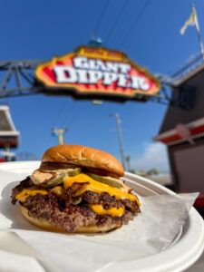 Smash burger on a plate with the Giant Dipper sign in the background.